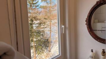 A bathroom with a window, a mirror, and a sink.