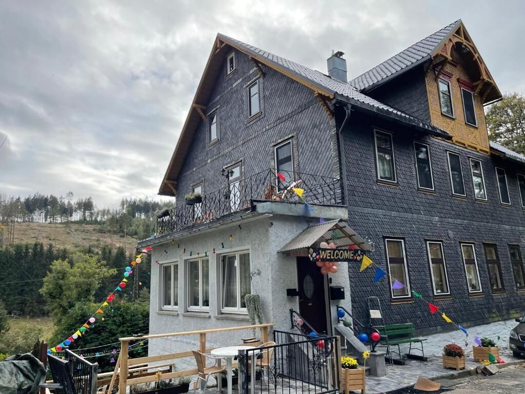 Un bâtiment à deux étages doté d’un balcon, d’une enseigne accueillante et d’un espace extérieur aménagé pour s’asseoir.