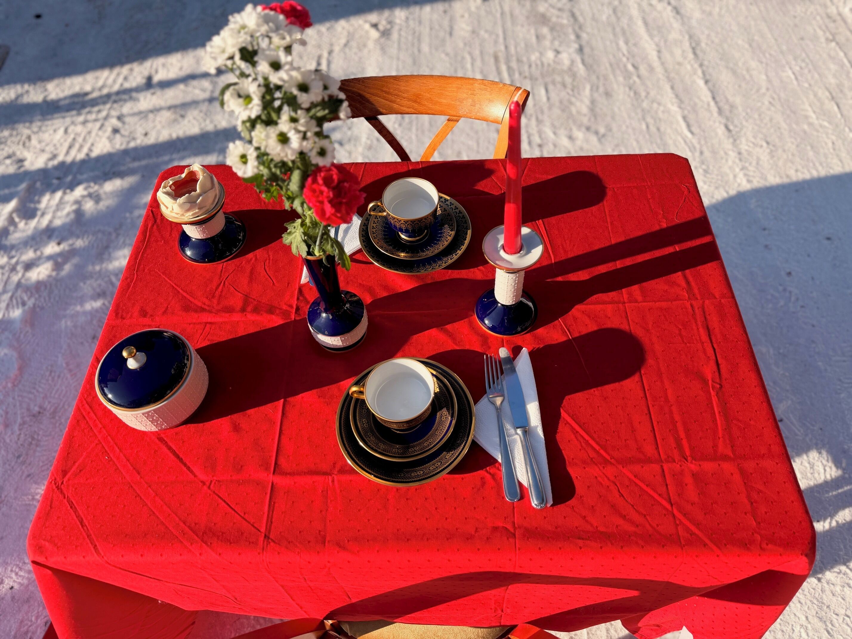 A table set with dinnerware, a vase with flowers, and a candle.