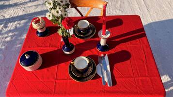 A table set with dinnerware, a vase with flowers, and a candle.