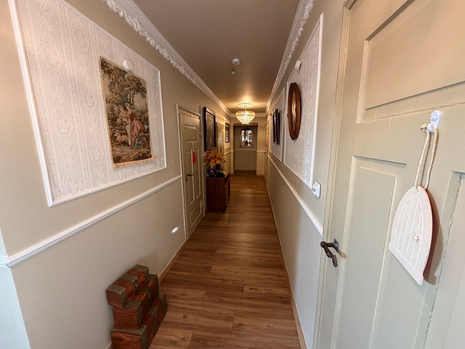 Un couloir doté d’un plancher en bois, de panneaux muraux décoratifs et d’une porte avec une poignée originale.