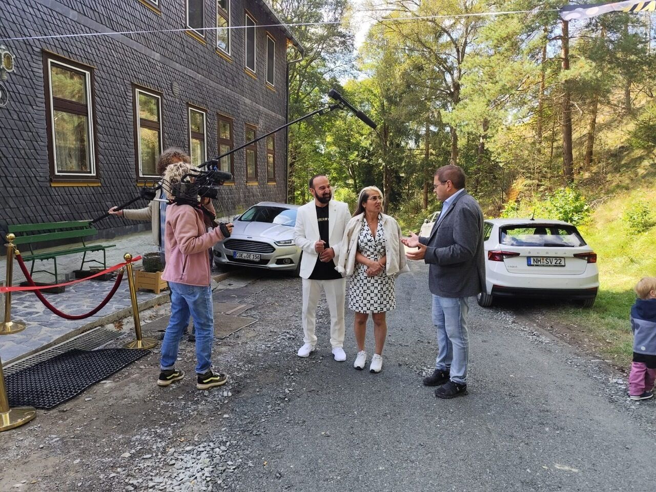 A group of people standing outside a building with a camera crew.