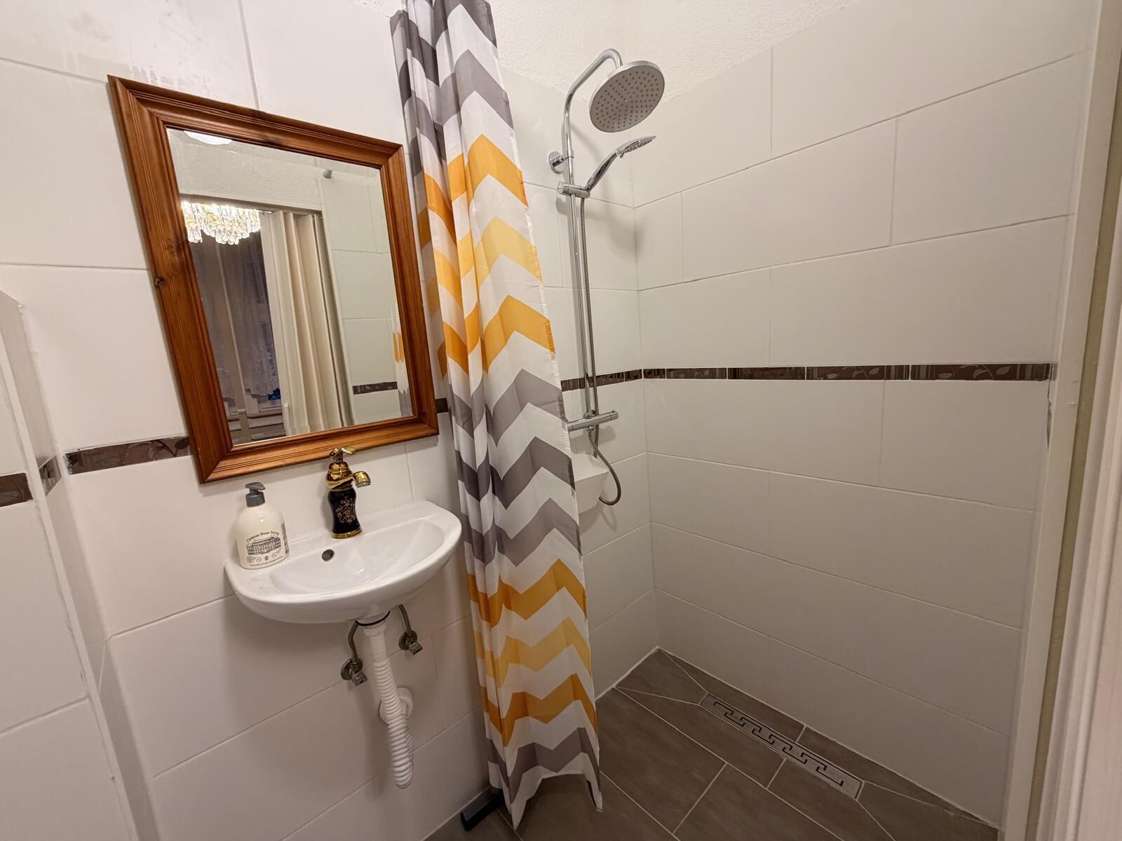 A small bathroom with a shower, a sink, and a mirror.