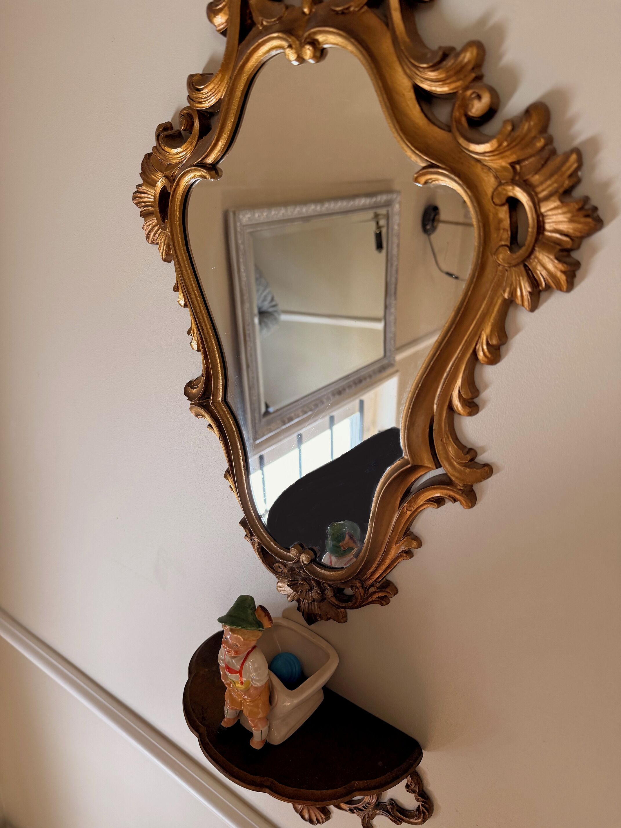 A mirror with an ornate gold frame on a wall.