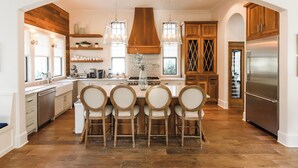 A spacious kitchen with a central island, wooden cabinets, and a stainless steel refrigerator. - Luxury in Old Seagrove  • Heated Pool  • Walk to Beach • Elevator • Widows Peak (Santa Rosa Beach)
