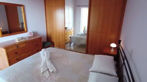 Un dormitorio con cama, cómoda, espejo y ventana.