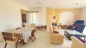 Una sala de estar con chimenea de piedra, un comedor con mesa y sillas, y un televisor en una esquina.