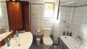 Un baño con lavamanos blanco, inodoro, bañera y ventana con diseño decorativo.