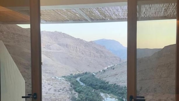 A room with a view of a mountainous landscape through a glass door. - WADINA RESORT   (Wadi Bani Khalid)