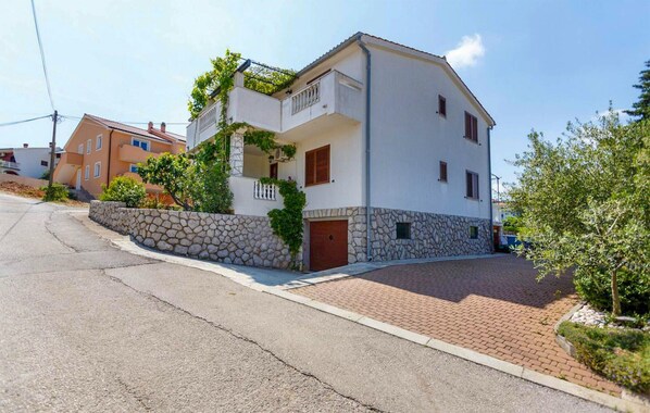 A two-story building with a stone wall and a paved driveway.