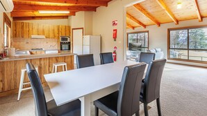 A modern kitchen with wooden cabinetry, a white countertop, and a dining area with a large table and chairs.