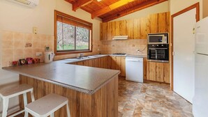 A kitchen with wooden cabinets, a granite countertop, a built-in oven, and a window.