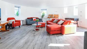 A modern living room with a sofa, armchair, coffee table, and a foosball table.