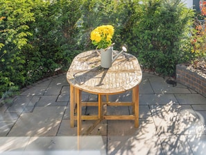 A round wooden table with a metal pitcher and flowers, surrounded by greenery. - 3 bedroom accommodation in Cradley, near Malvern (Cradley, near Malvern)