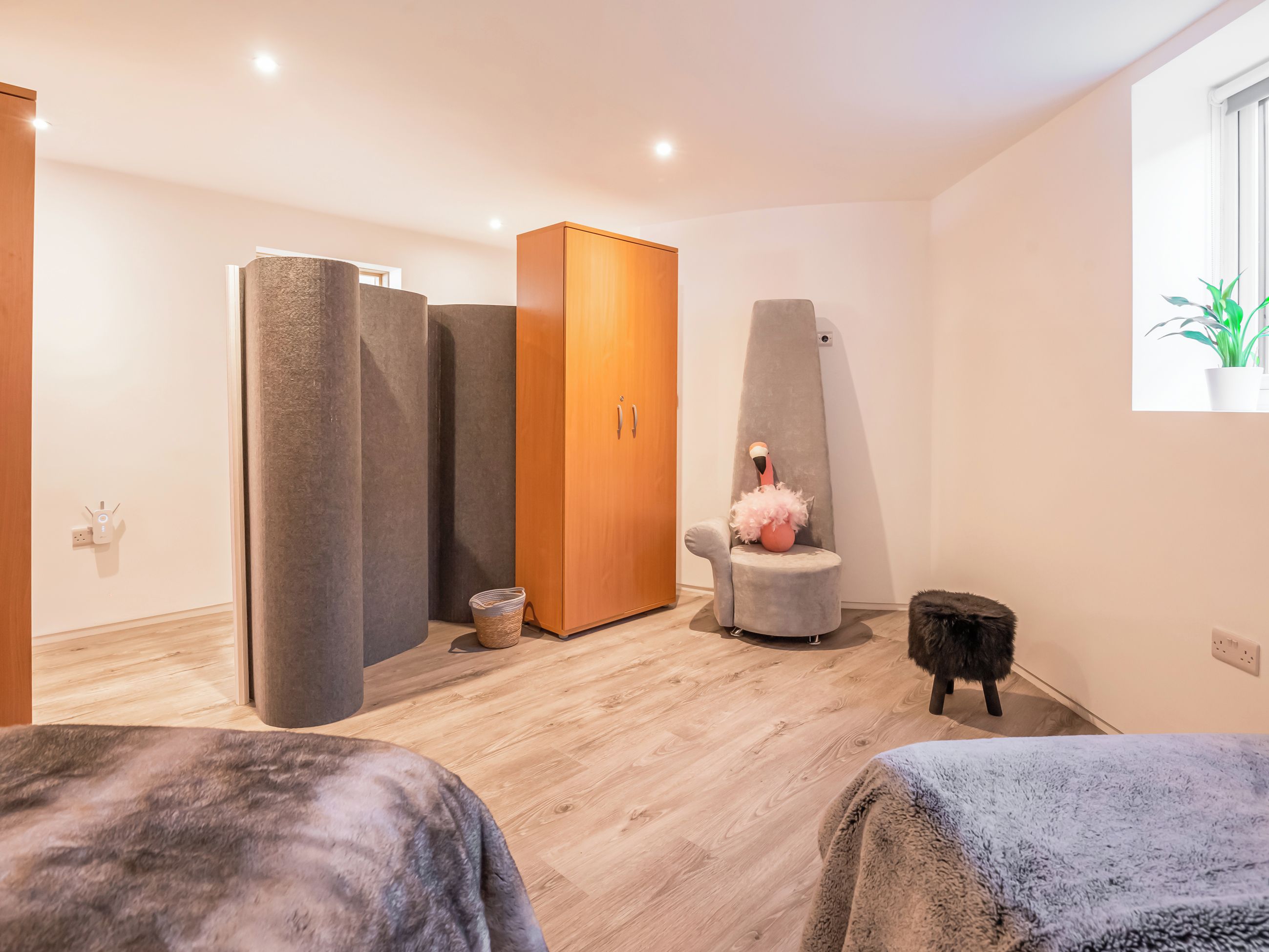 A modern room with a wardrobe, a tall chair, a small table, and a bed.