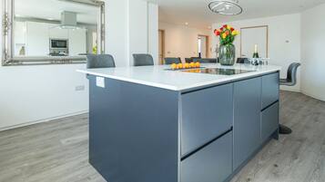 A modern kitchen with a central island, a large mirror, and a dining area with chairs.