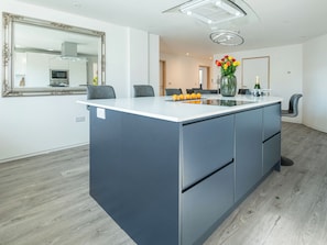 A modern kitchen with a central island, a large mirror, and a dining area with chairs. - 3 bedroom accommodation in Cradley, near Malvern (Cradley, near Malvern)