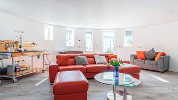 A modern living room with a red sofa, a grey sofa, a glass coffee table, and a small round table.