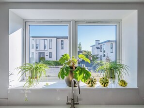 A modern kitchen with a large window, a sink, and various potted plants. - 3 bedroom accommodation in Cradley, near Malvern (Cradley, near Malvern)