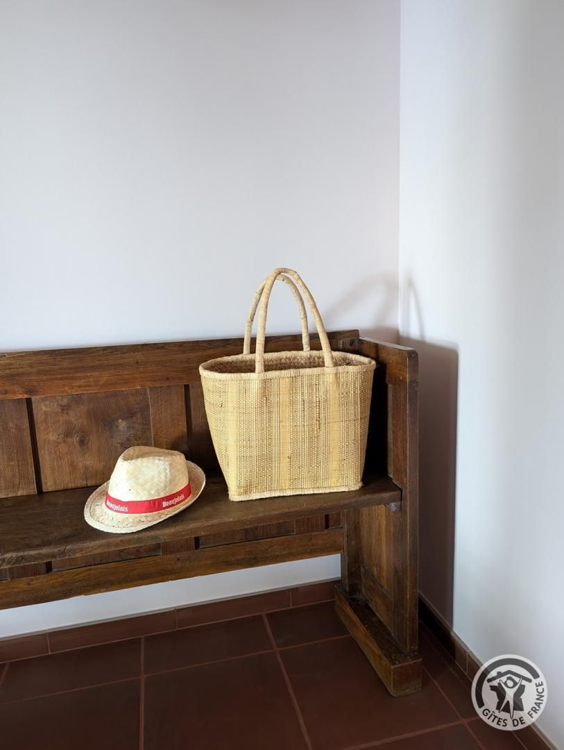 Un banc en bois sur lequel sont posés un panier tressé et un chapeau de paille.