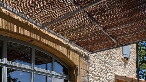 A stone building with large windows and a wooden pergola. - La Maison du Crêt - RIVOLET (RIVOLET)