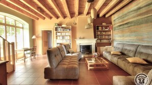A cozy living room with a fireplace, bookshelves, and a sofa. - La Maison du Crêt - RIVOLET (RIVOLET)