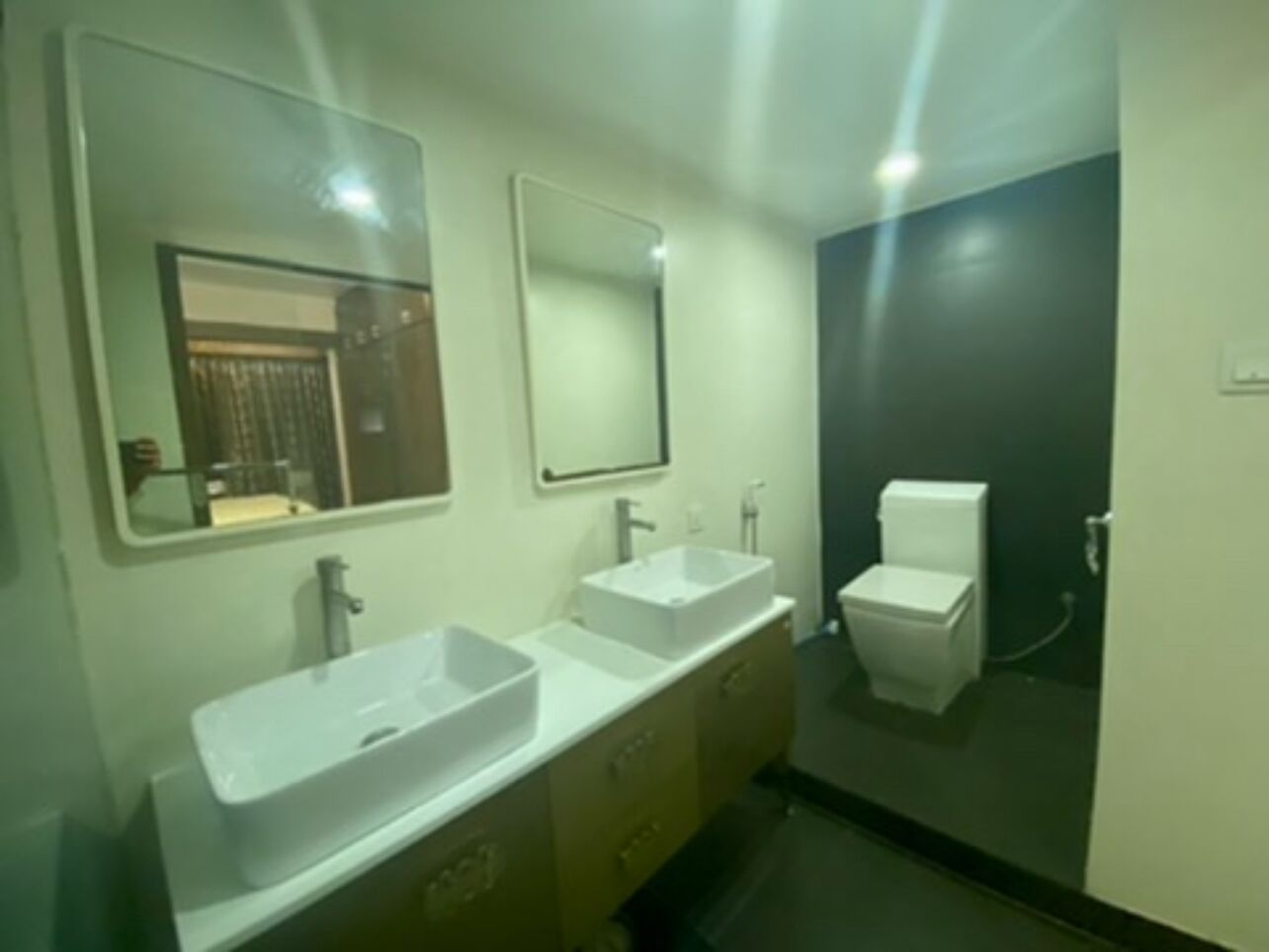 Une salle de bain avec deux lavabos, des toilettes et un miroir.
