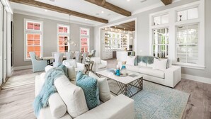 A spacious living room with a high ceiling, exposed wooden beams, and large windows. - "Watercolor Brushtrokes" Heated Private Pool/Golf Cart/ Walk to Camp Pool/Bikes (Santa Rosa Beach)