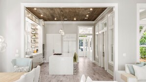 A modern kitchen with white cabinetry, a central island, and a wooden ceiling. - "Watercolor Brushtrokes" Heated Private Pool/Golf Cart/ Walk to Camp Pool/Bikes (Santa Rosa Beach)
