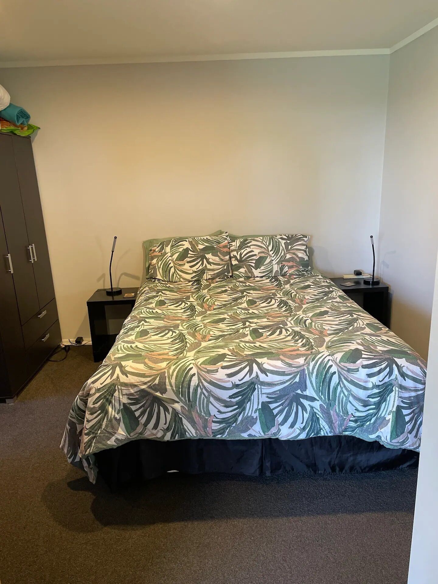 Quarto com cama, mesa de cabeceira, cômoda e abajur.