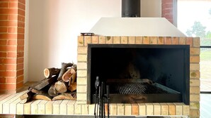 Ein Kamin aus Ziegelsteinen mit Schornstein, Holzscheiten und einem Besen.