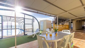 A covered outdoor area with a pool, lounge chairs, and a table with drinks. - Casa Rural el Olivo centenario (Perin)