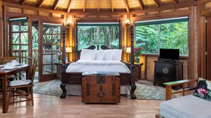 A wooden room with a bed, a desk, and a television. - Rainforest Retreat in Volcano Village (Volcano)