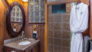 A bathroom with a wooden vanity, a sink, a mirror, and a bathtub. - Rainforest Retreat near Hawaii Volcanoes National Park (Volcano)