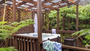 A hot tub in a wooden gazebo surrounded by lush ferns and tropical plants. - Rainforest Retreat near Hawaii Volcanoes National Park (Volcano)