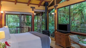 A bedroom with a bed, a television, a wooden dresser, and a chair. - Rainforest Retreat near Hawaii Volcanoes National Park (Volcano)