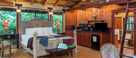 A wooden room with a bed, a desk, a chair, a small table, and a television.