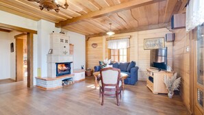 Ein gemütliches Wohnzimmer mit Kamin, Holzboden und Fernseher.