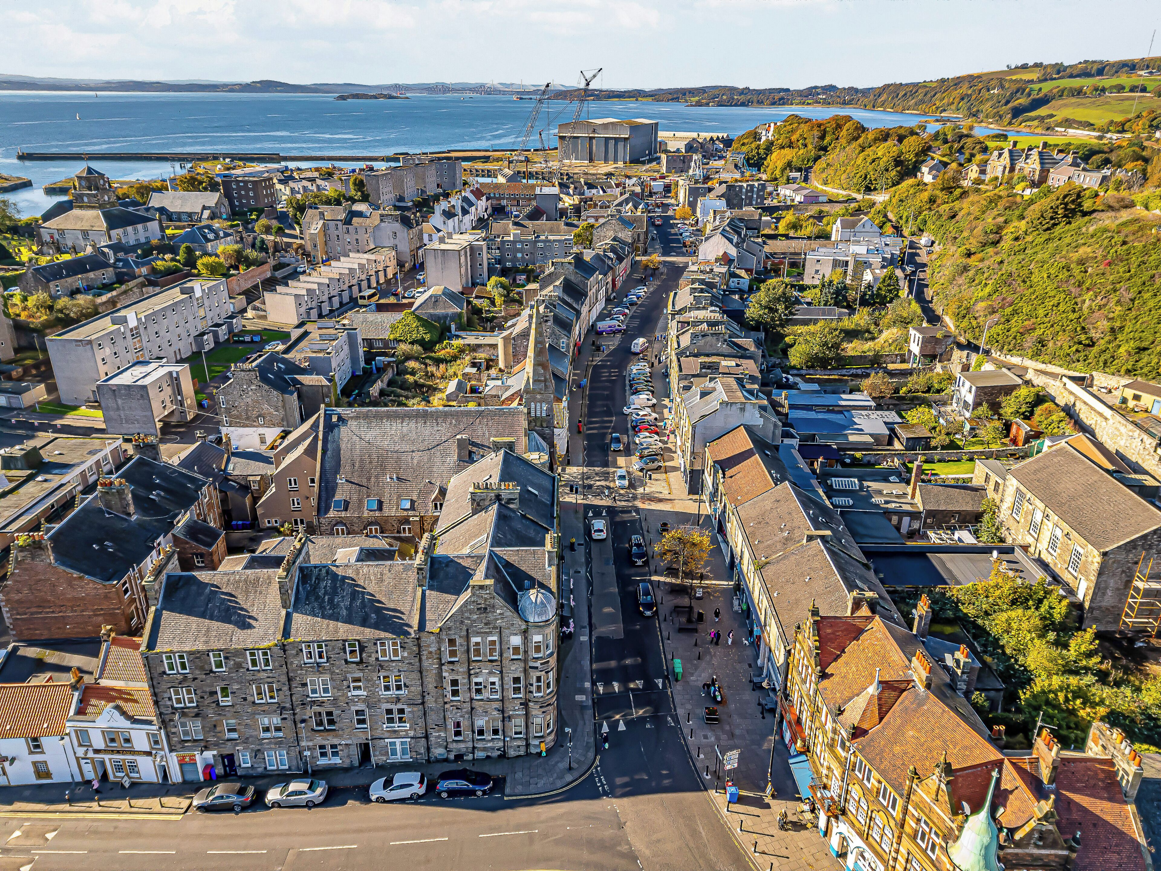 Vue aérienne d’une ville côtière avec ses bâtiments historiques, sa rue principale et son port.
