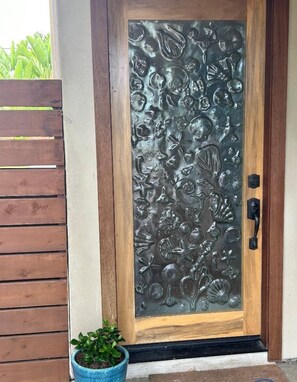A door with a decorative glass panel featuring embossed sea shells and leaves.