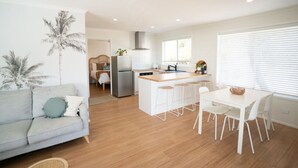 Una cocina moderna con armarios blancos, una isla central con taburetes y una mesa de comedor con sillas.