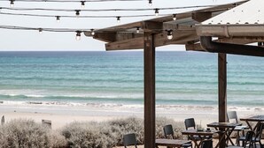 Un patio frente a la playa con mobiliario exterior y vistas al océano.