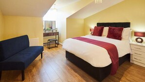 A bedroom with a large bed, a desk, and a chair.