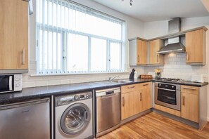 A modern kitchen with stainless steel appliances, wooden cabinets, and a large window providing natural light. -  Abigail's Apartment (Heath Town)