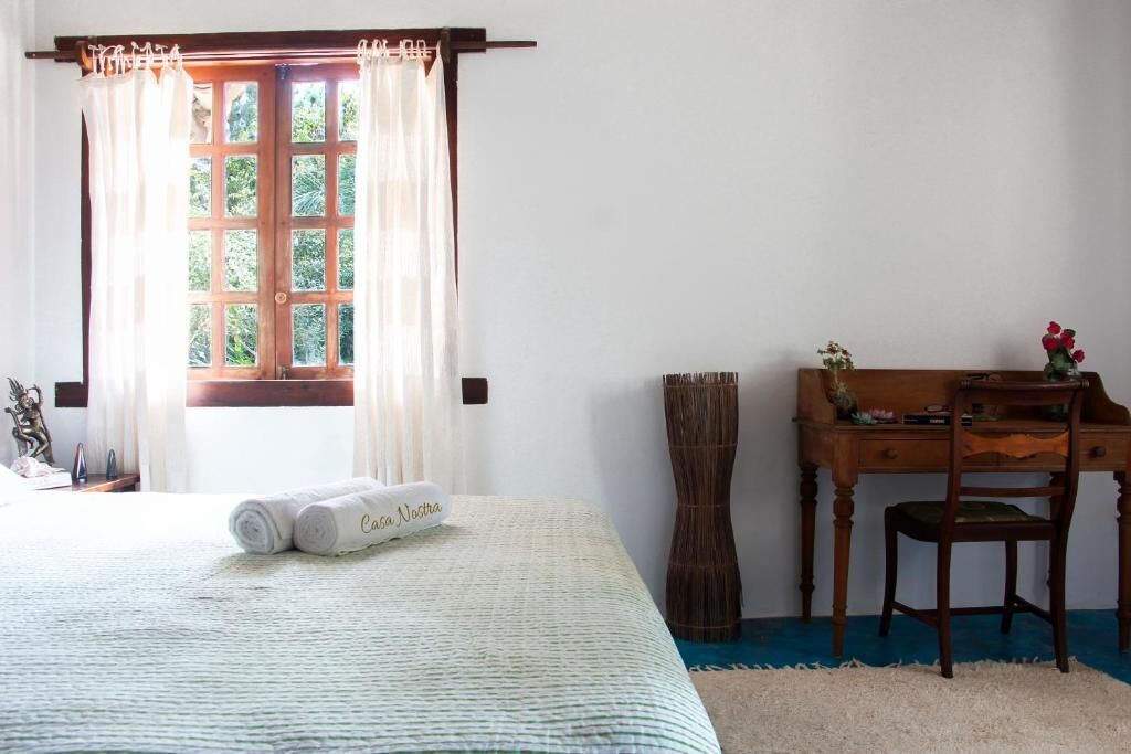 Un dormitorio con cama, escritorio, silla y ventana con cortinas.