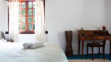 Un dormitorio con cama, escritorio, silla y ventana con cortinas.