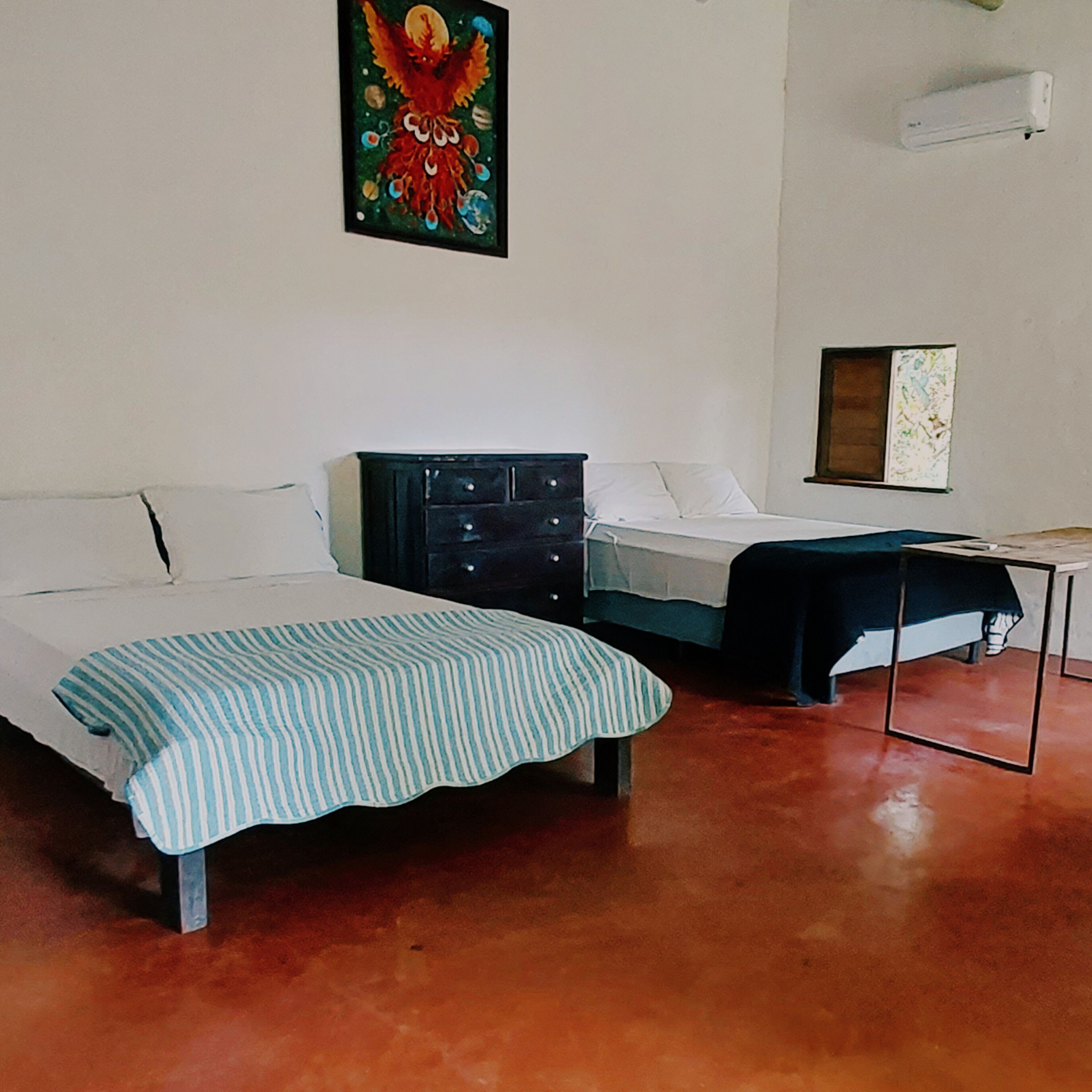 A bedroom with two beds, a dresser, and a table.