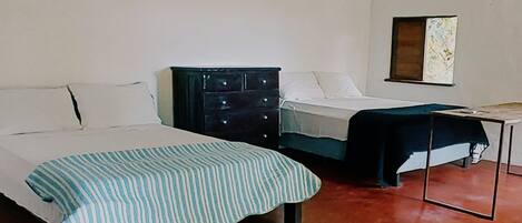 A bedroom with two beds, a dresser, and a table.