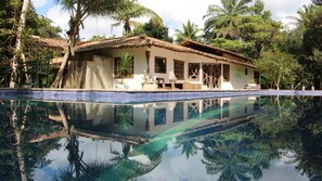 Una casa con piscina rodeada de palmeras.