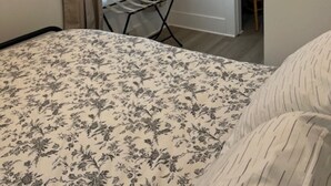 A bedroom with a bed, a window with curtains, a drying rack, and a door leading to another room. - Charming 2-bedroom home in Odessa (Odessa)